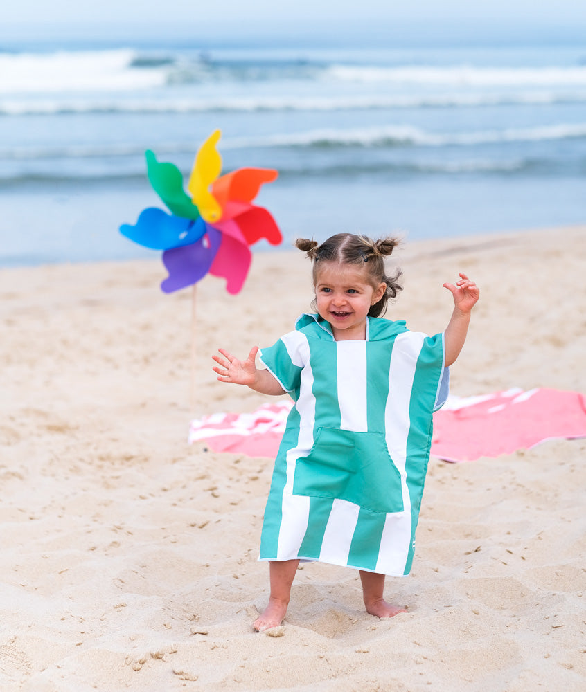 une petite fille joue sur la plage vêtue d'un poncho en microfibre