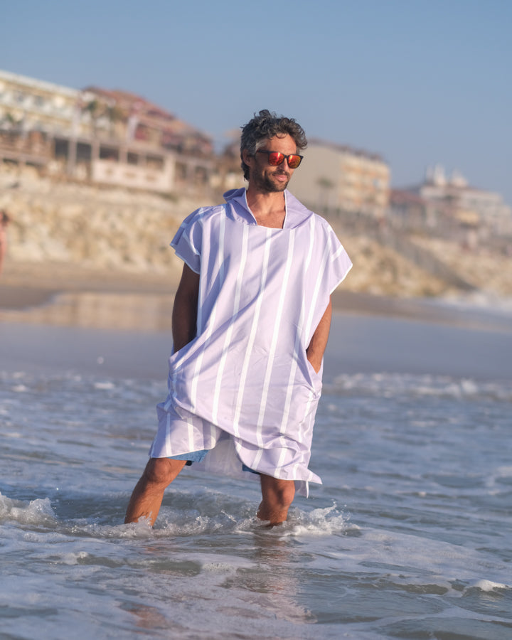 un homme avec les pied dans l'eau avec son poncho de plage