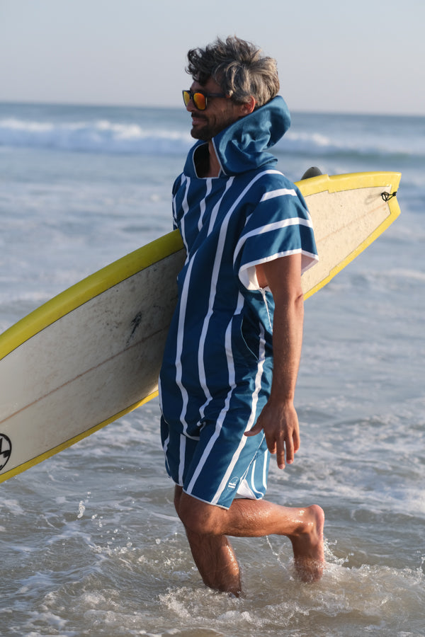 un homme pratiquant le surf qui a un poncho de plage