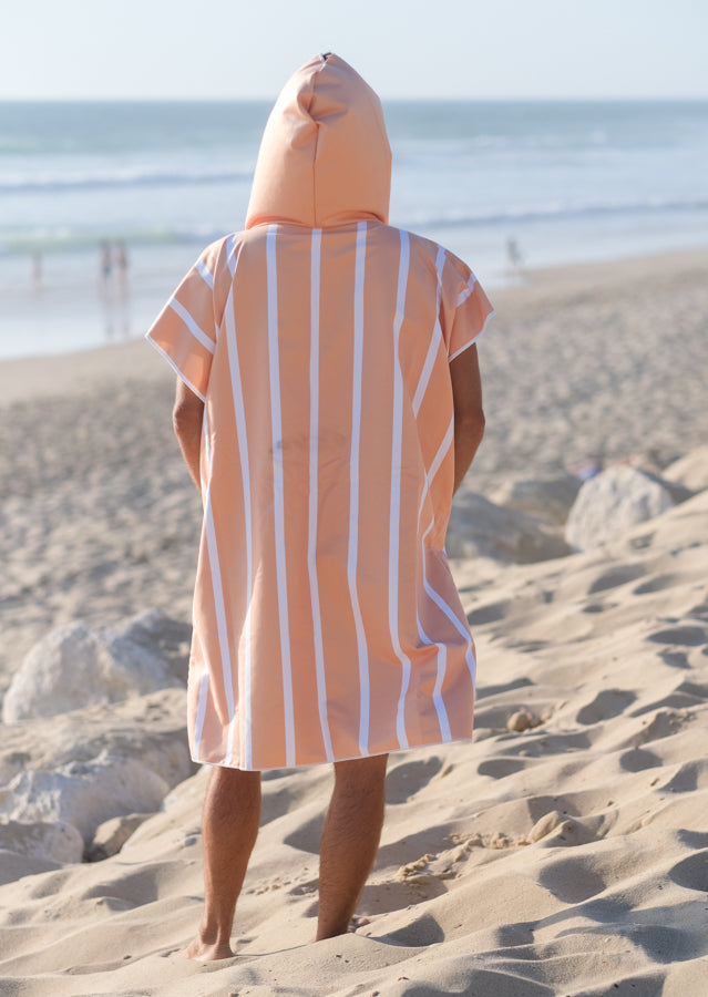 personne de dos avec un poncho à capuche de couleur pêche