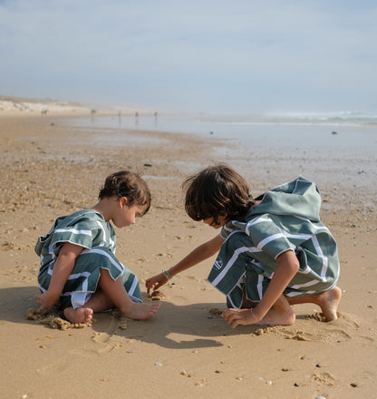 deux enfants qui jouent dans le sable avec leur poncho