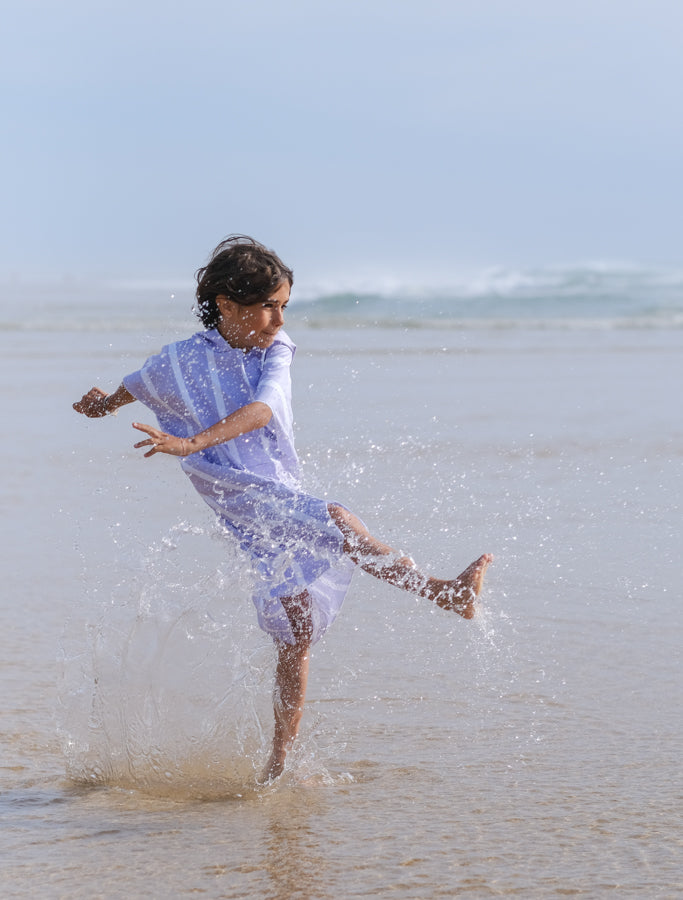 enfant qui s'amuse dans l'eau avec son poncho en microfibre