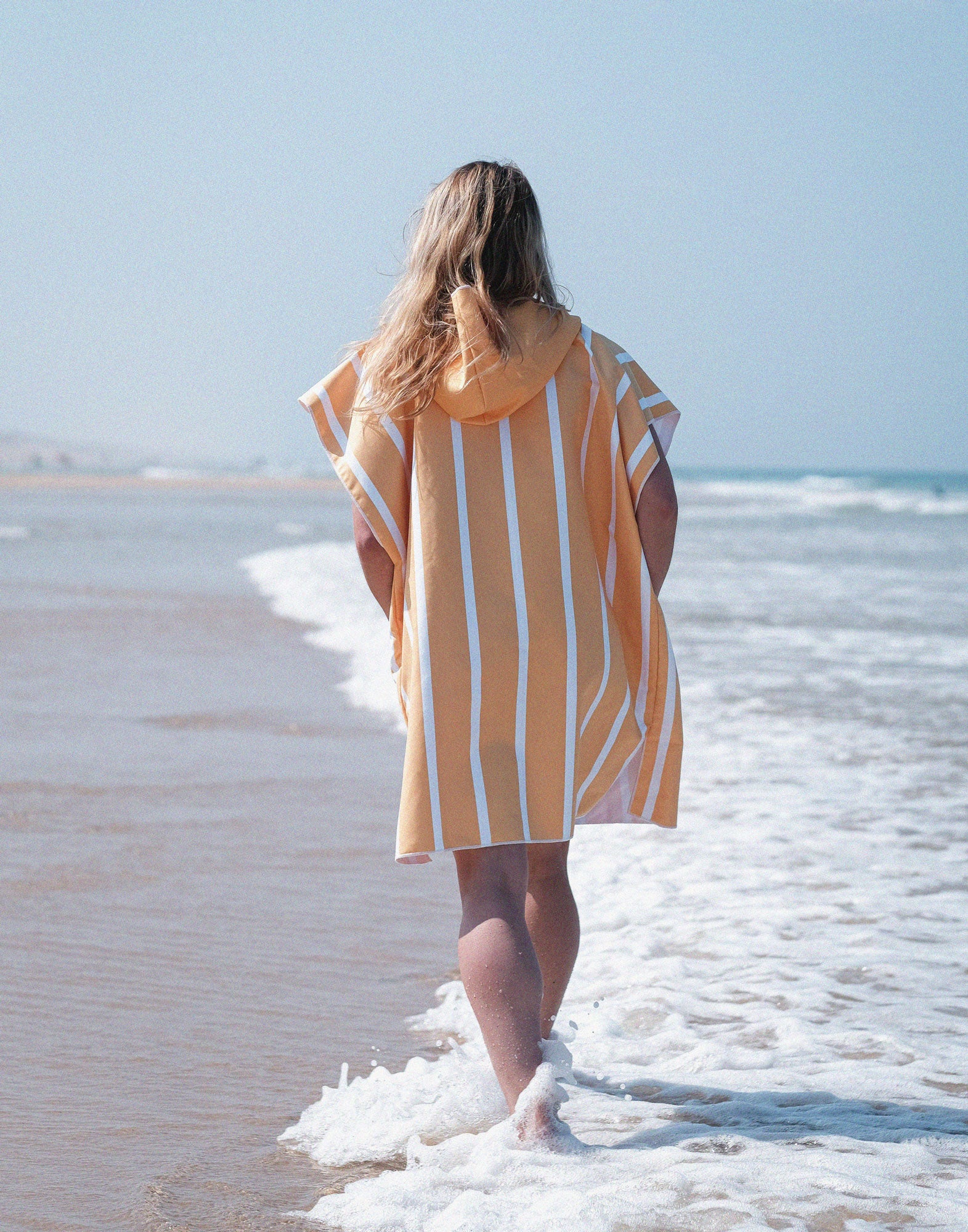 fille qui marche sur la plage en poncho microfibre à rayures orange