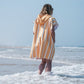 fille de dos sur la plage en poncho à rayures 