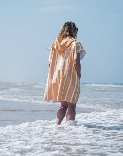 fille de dos sur la plage en poncho à rayures 