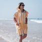 fille qui marche dans l'eau avec un poncho microfibre à rayures