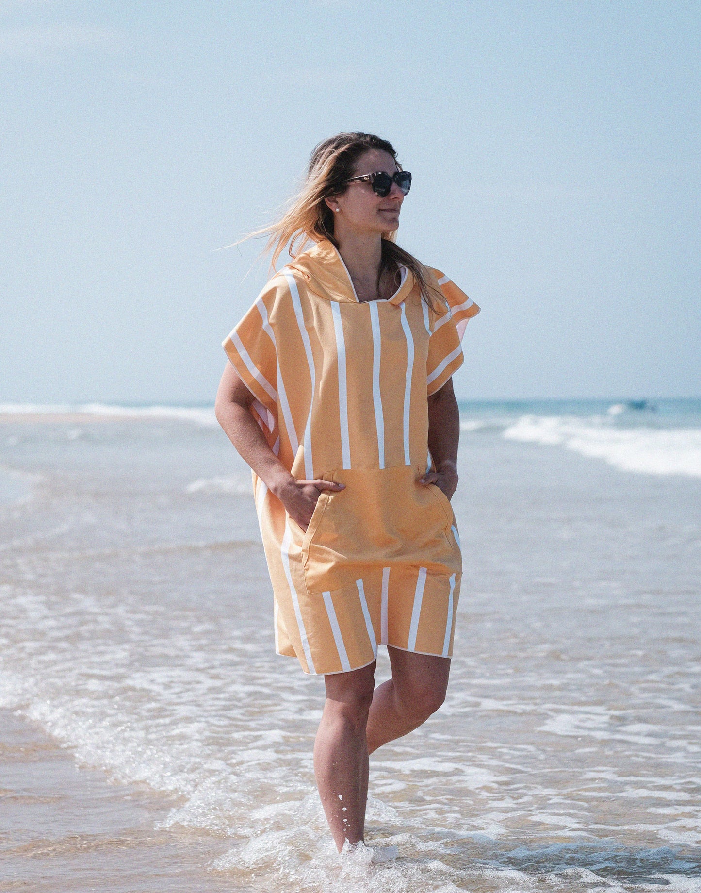 fille qui marche dans l'eau avec un poncho microfibre à rayures