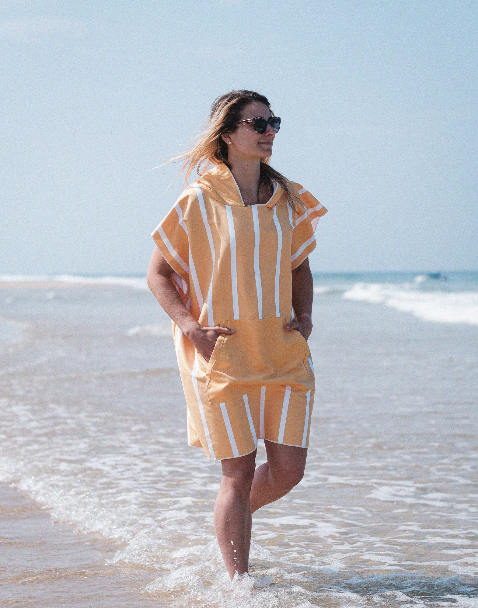fille qui marche dans l'eau avec un poncho microfibre à rayures