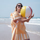 fille avec un ballon sur la plage avec un poncho rayée en microfibre orange et blanc