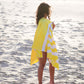 femme qui regarde la mer et qui a une serviette en microfibre jaune