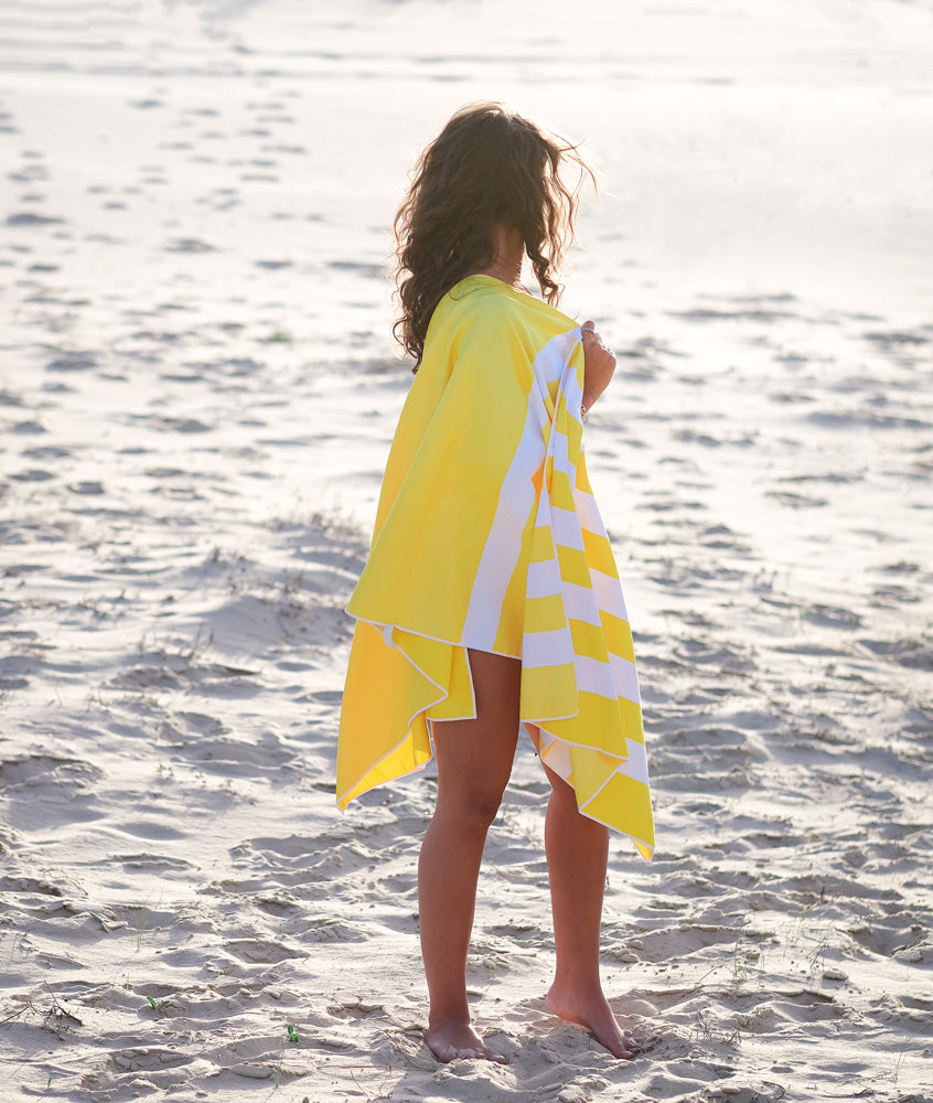femme qui regarde la mer et qui a une serviette en microfibre jaune