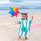 une petite fille joue sur la plage vêtue d'un poncho en microfibre