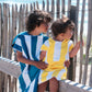 deux enfants assis sur une planche de bois qui regarde la mer vêtus d'un poncho de plage en microfibre 
