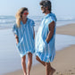 couple sur la plage qui rit portant un poncho de plage bleu ciel