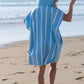 femme de dos avec un poncho en microfibre bleu ciel à rayure