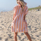 femme sur la plage qui sourit en portant son poncho de plage 
