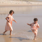 deux enfants qui courent dans l'eau avec leur poncho à rayure orange
