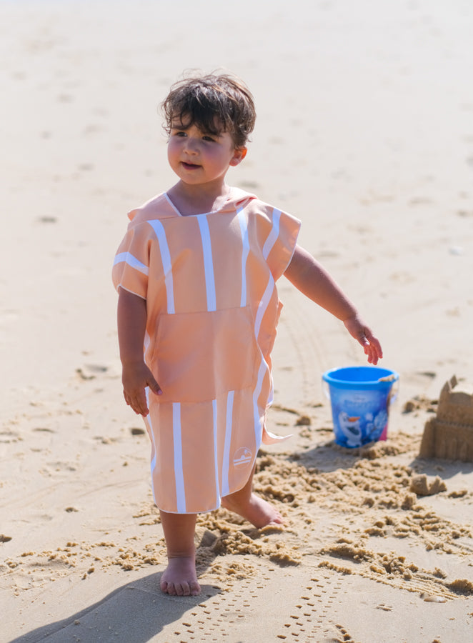 enfant qui fait un château de sable qui porte poncho de plage en microfibre