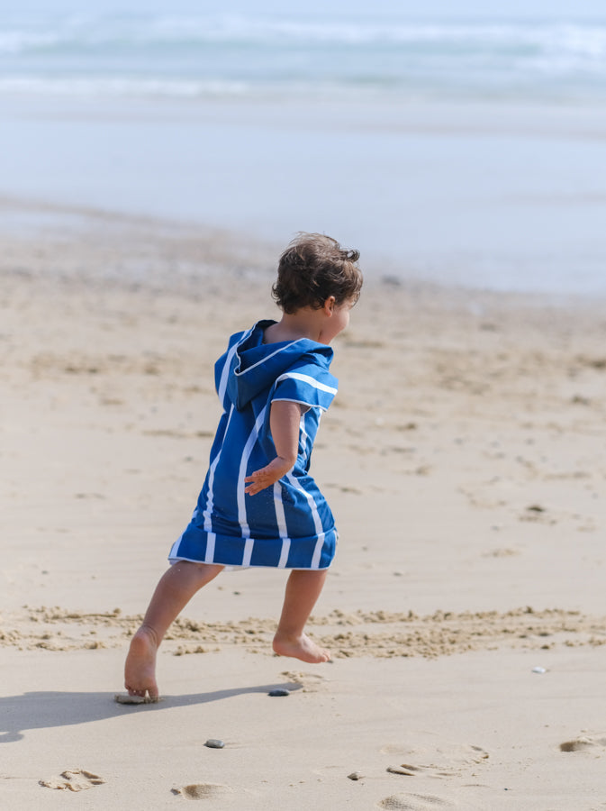enfant qui court sur la plage avec un poncho en microfibre bleu