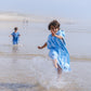 deux enfants qui courent dans l'océan avec des ponchos beachee