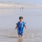 enfant avec les pieds dans la mer portant un poncho de plage bleu 