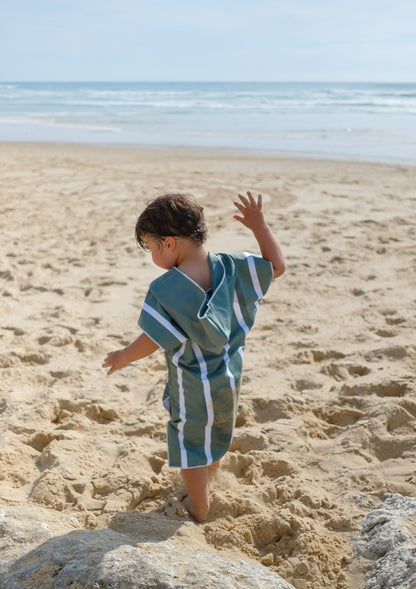 un enfant qui marche dans le sable avec son poncho vert