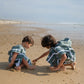 deux enfants qui jouent dans le sable avec leur poncho